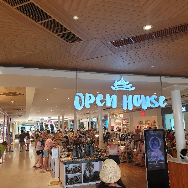 Seminyak Village OPEN HOUSE 라는 네온 간판이 보인다. 매대에 구경하는 사람들이 많다.