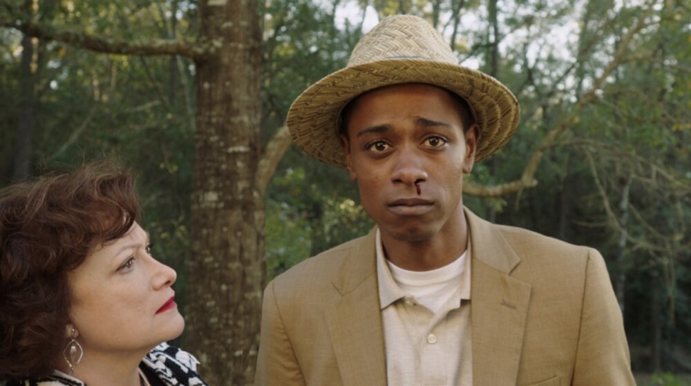 영화 겟 아웃 스틸컷 &ndash; 중절모를 쓴 남성이 코피를 흘리며 정원에서 서 있는 장면