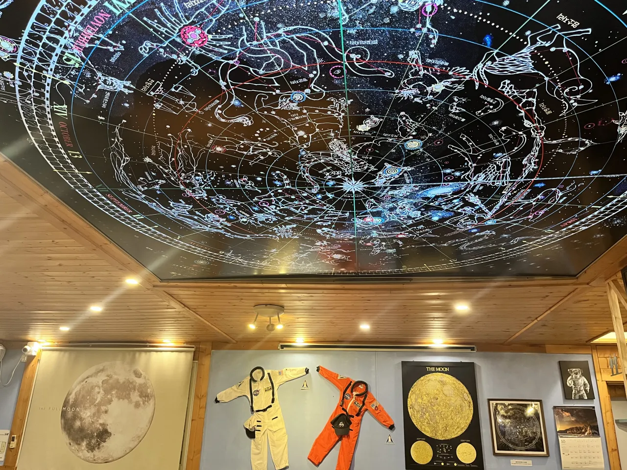 주황색-우주복-노란색-우주복-위에-천문-별자리-지도가-천장에-그려짐