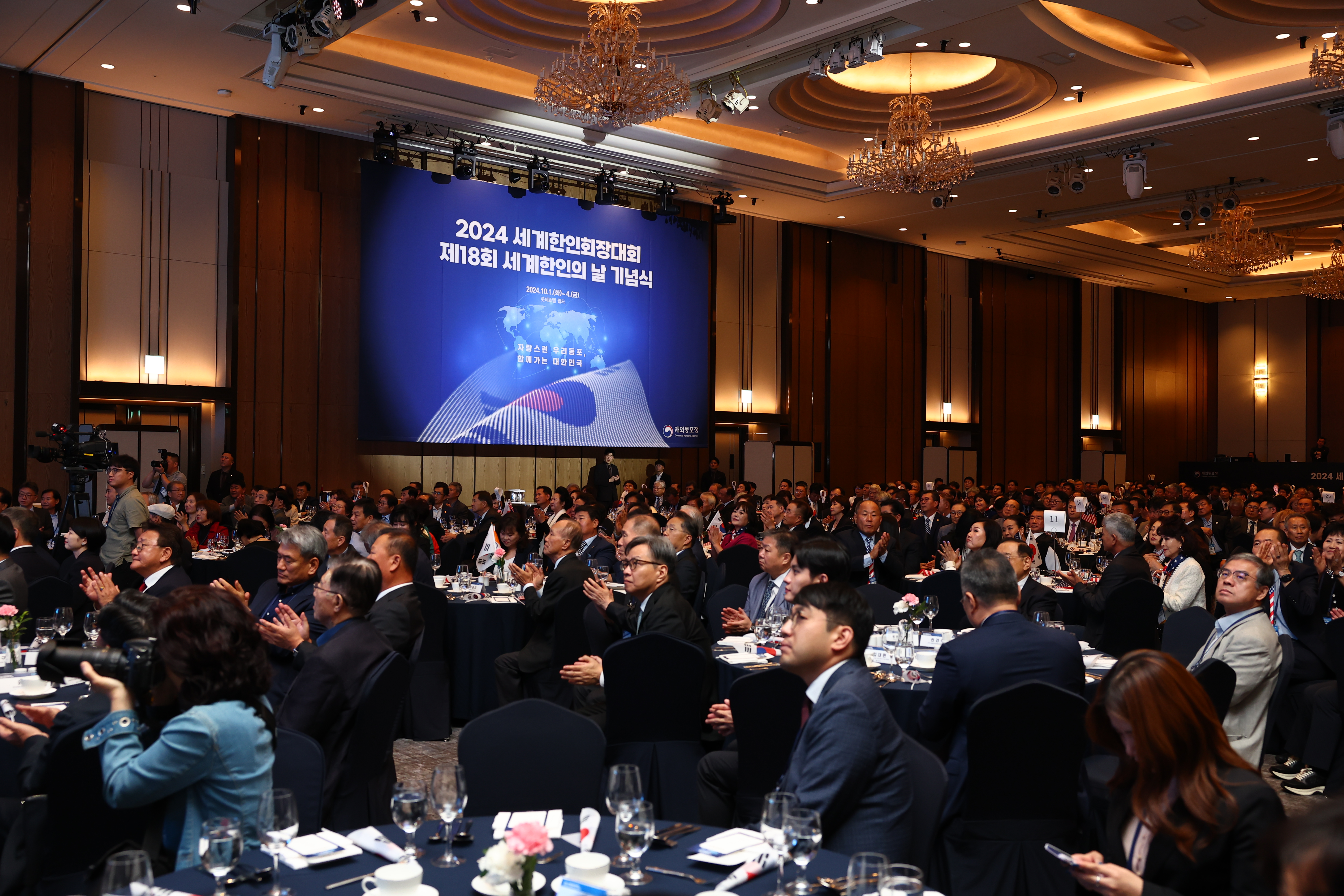2024년 10월 1일 서울 송파구에 있는 롯데호텔 월드에서 열린 2024년 세계한인회장대회 개회식 장면1&amp;#44; 원형 탁작에 나눠 앉은 참석자들이 벽면에 위치한 스크린을 보고 있다.