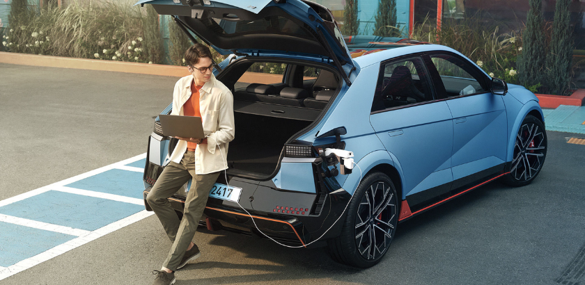 퍼포먼스 블루 색상의 아이오닉 5N의 배터리를 이용해 랩탑을 충전하는 모습