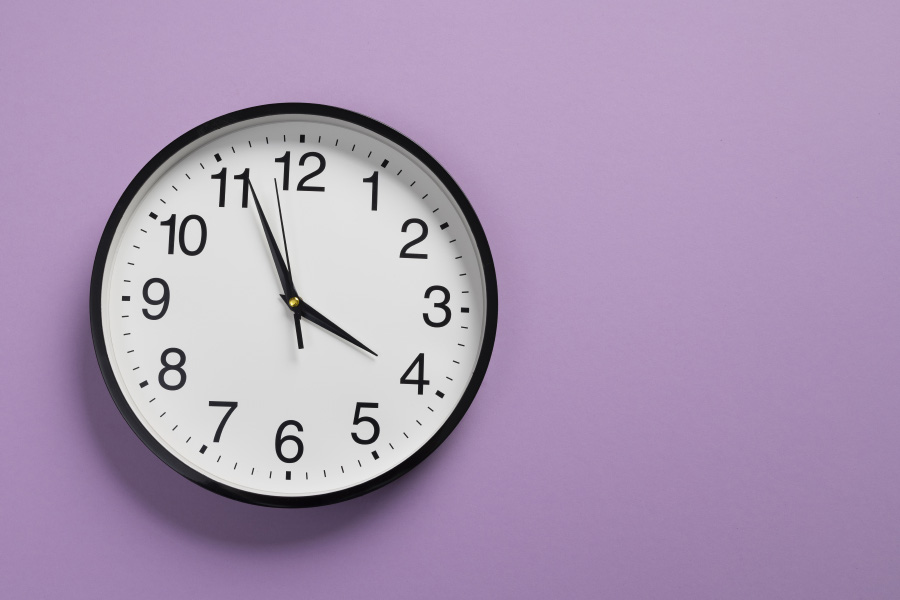 보라색 벽에 달려 있는 동그란 시계가 3시 56분 58초를 가리키고 있는 것을 찍은 사진