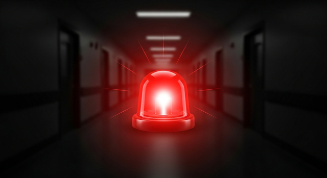 어두운 병원 복도 위에 붉게 빛나는 사이렌을 강조한 응급 상황 이미지