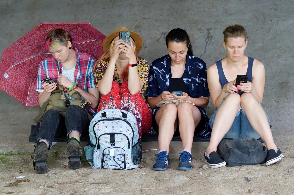 여성 4명이 앉아서 스마트폰을 보고있는 사진