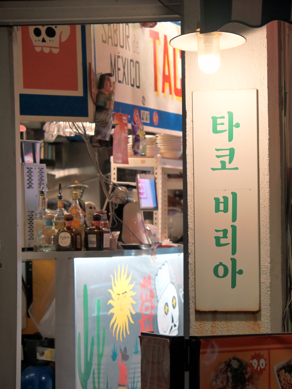 벽면에 초록색 글씨로 쓴 타코 비리아 간판과 내부가 살짝 보인다.