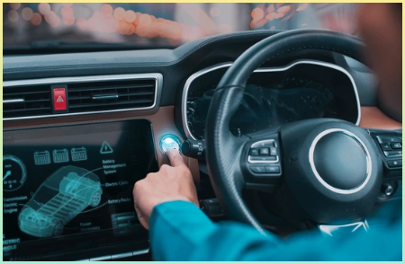 운전자가 황혼 무렵 전기 자동차의 대화형 대시보드에서 시작 버튼을 활성화하는 모습.