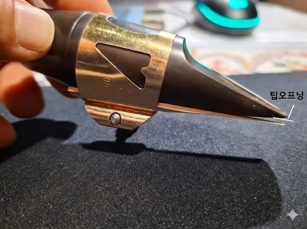 색소폰 마우스피스 끝부분과 리드 사이의 간격인 '팁 오프닝(Tip Opening)'을 시각적으로 보여주는 측면 확대 사진 및 교육용 이미지