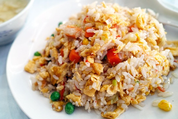 계란볶음밥이 하얀 접시에 담겨있다.