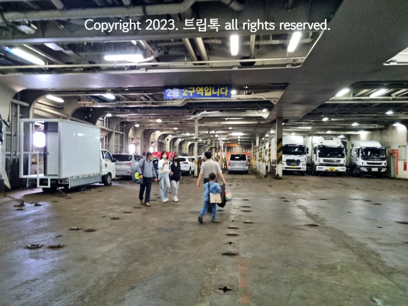 선박내 주차장으로 사람들이 차를 찾고 있다. 큰 차들이 주차되어있다.