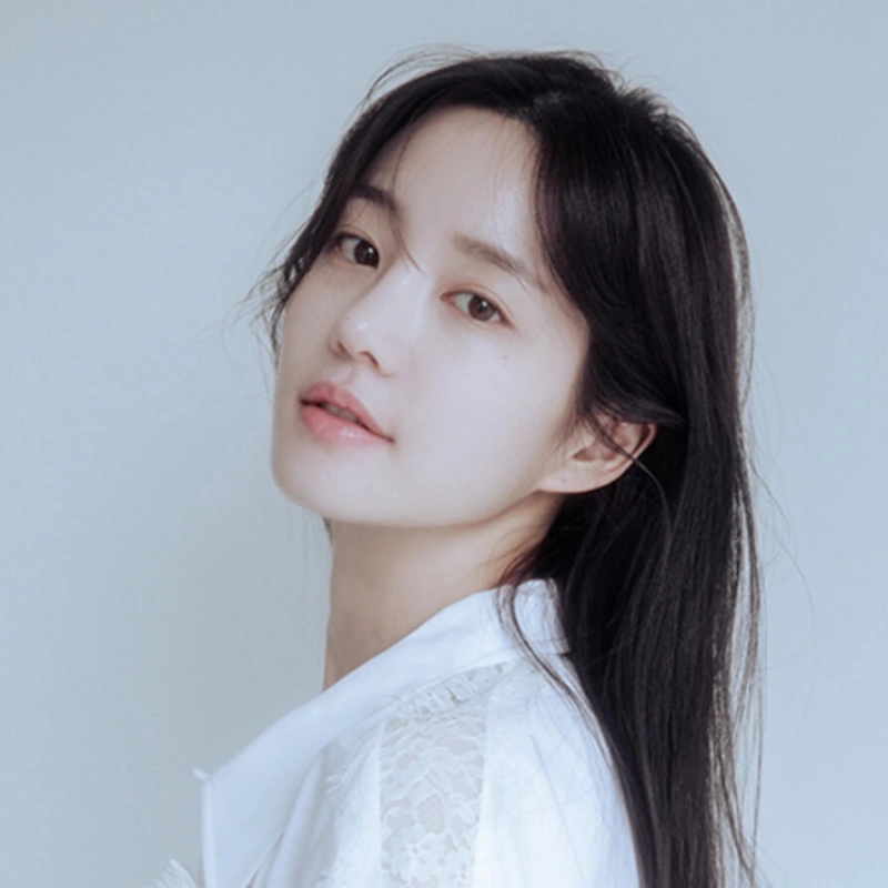 흰 배경에 검은 긴 머리에 흰색 셔츠를 입고 서 있는 배우 이유비