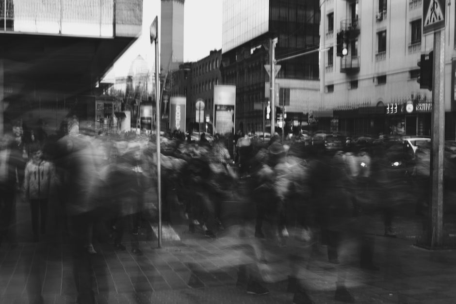 Blurred black and white city scene captures the motion of people crossing the street.