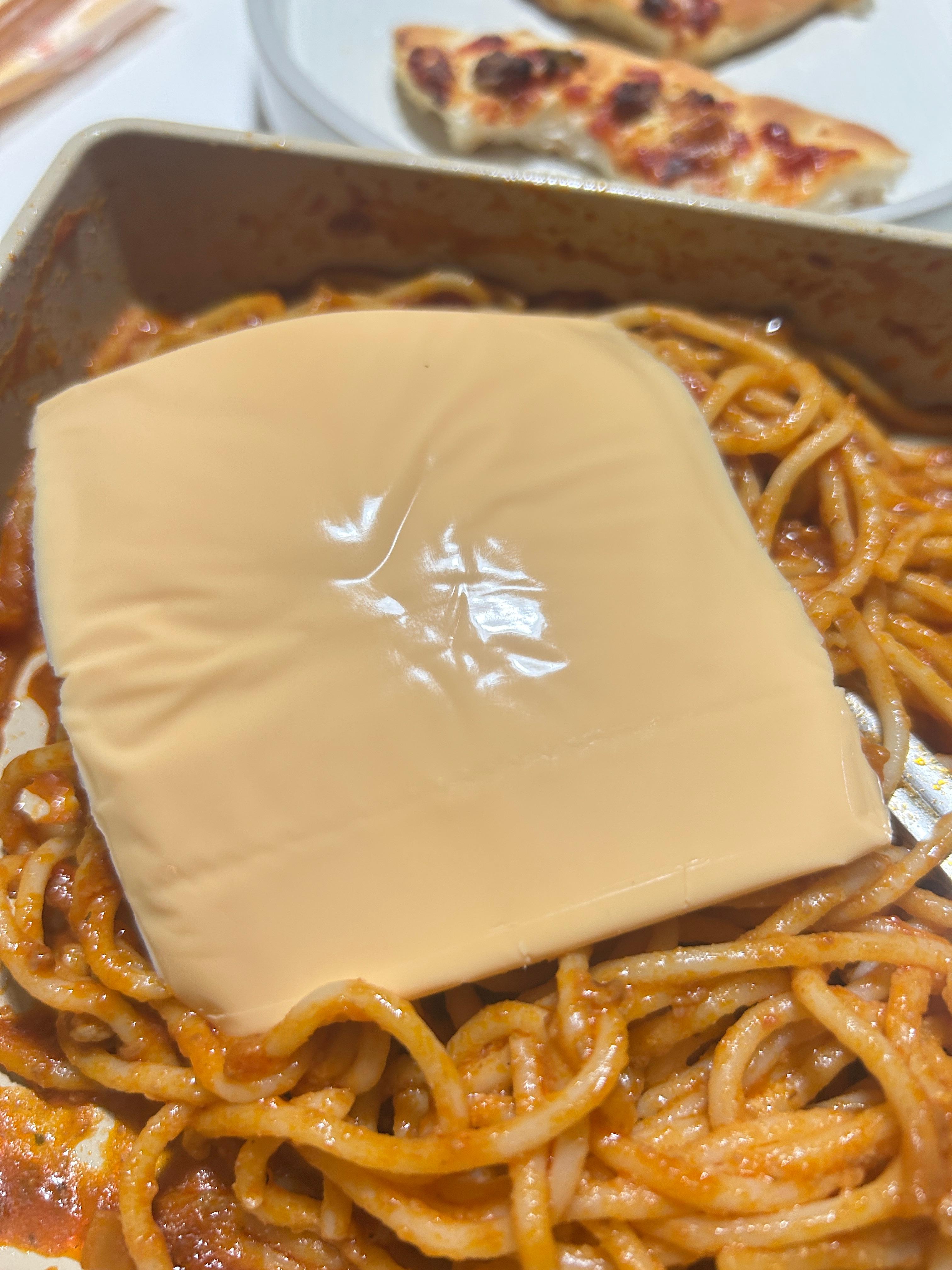 토마토 스파게티 위에 체다 치즈 한 장을 올린 모습