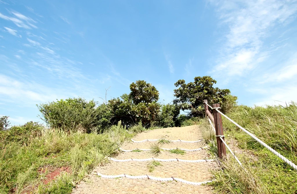 경사가 시작되는 구간의 밧줄 난간과 멍성이 깔려 있는 모습 사진 입니다.