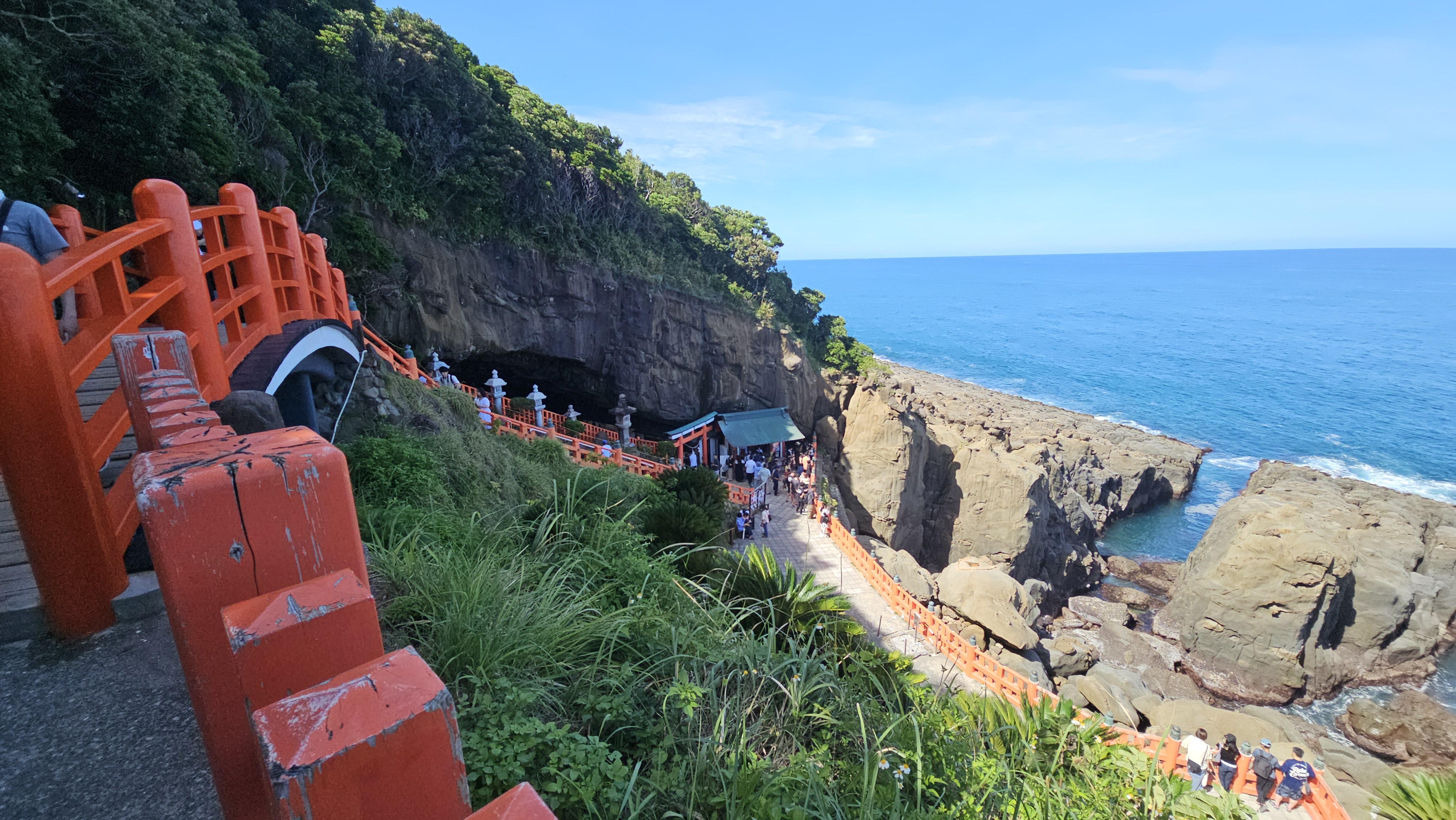 붉은 난간과 동굴 입구, 해안 절벽과 바위, 태평양을 한 컷에 담은 우도신궁의 전경