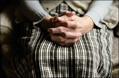 노인 무릎 위 손 모은 모습