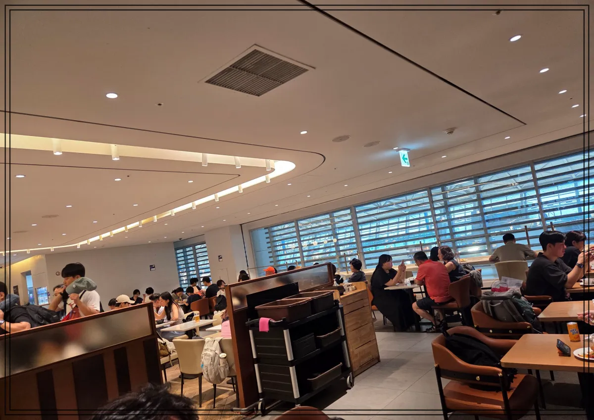 인천공항-마티나-라운지-내부-전경-넓은-공간에-많은-사람들이-앉아-식사하거나-대화하고-있으며-창가-좌석도-여러-명-이용중임-천장은-곡선형-조명으로-디자인되어-밝고-쾌적한-분위기를-연출함-중앙에는-트레이-수거용-카트가-놓여있고-라운지-전체적으로-혼잡한-상태임