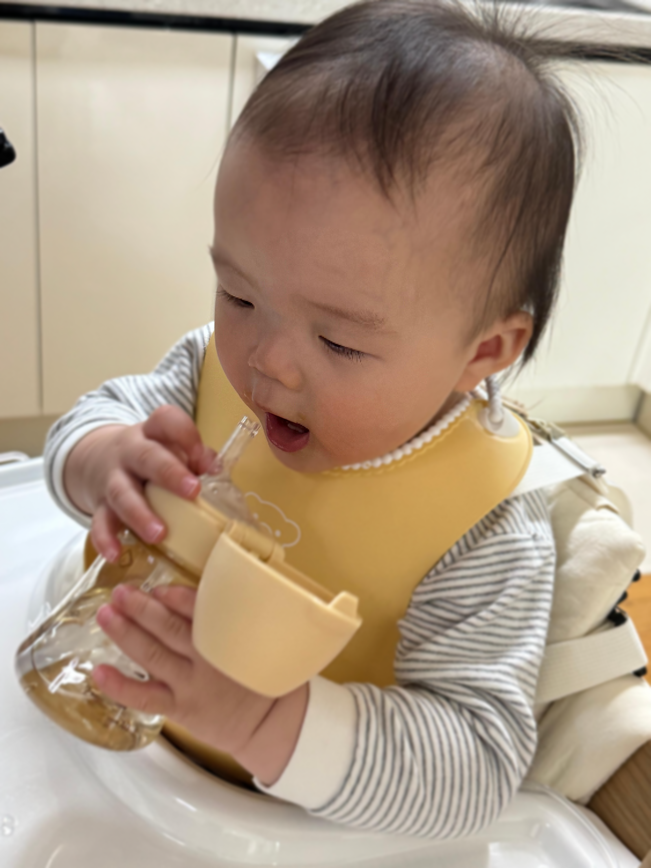 노란색 베이비뵨 소프트 이유식 턱받이를 착용하고 빨대컵으로 물을 마시는 11kg 돌아기 실사용 모습