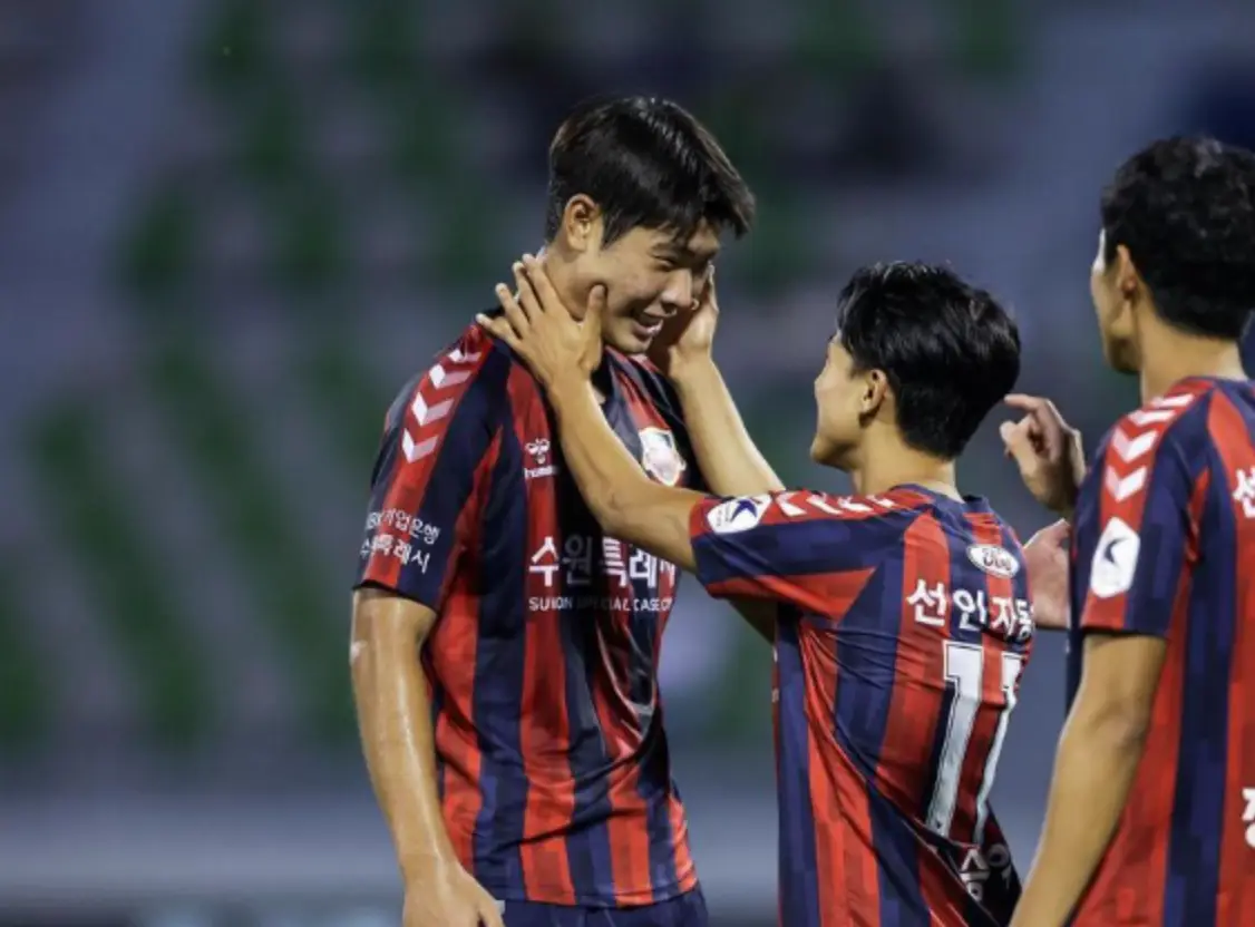 이영준- 붉고 파란 세로줄무늬 유니폼을 입은 이영준을 동료선수들이 두볼을 만지며 칭찬하는 장면