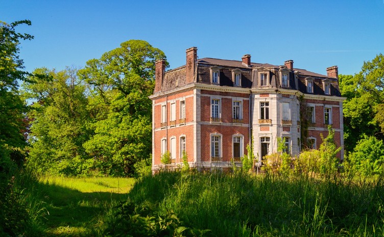 a red brick mansion in the middle of lush woods