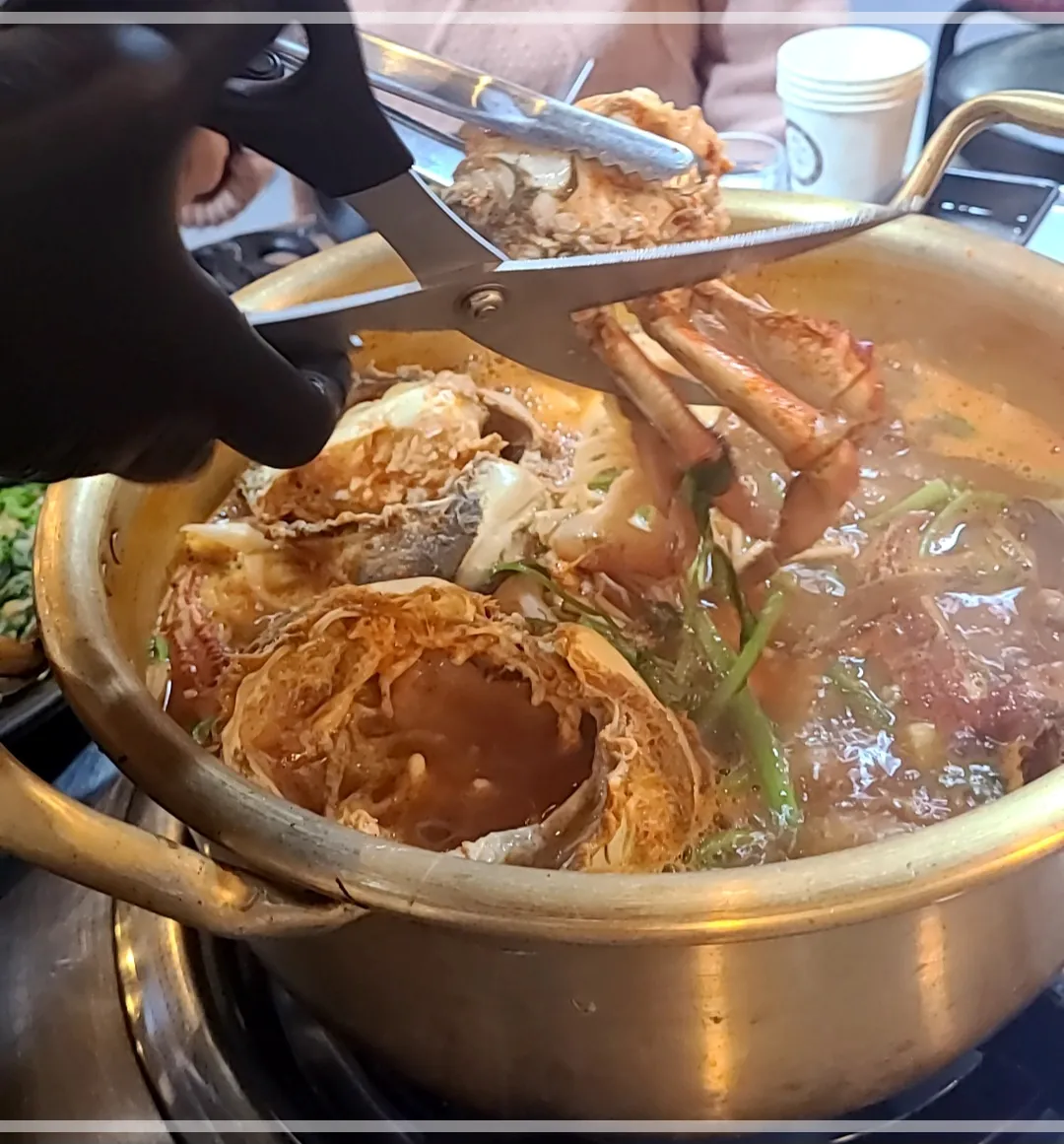 양은냄비 안에 밤게탕을 가위로 가르는 모습
