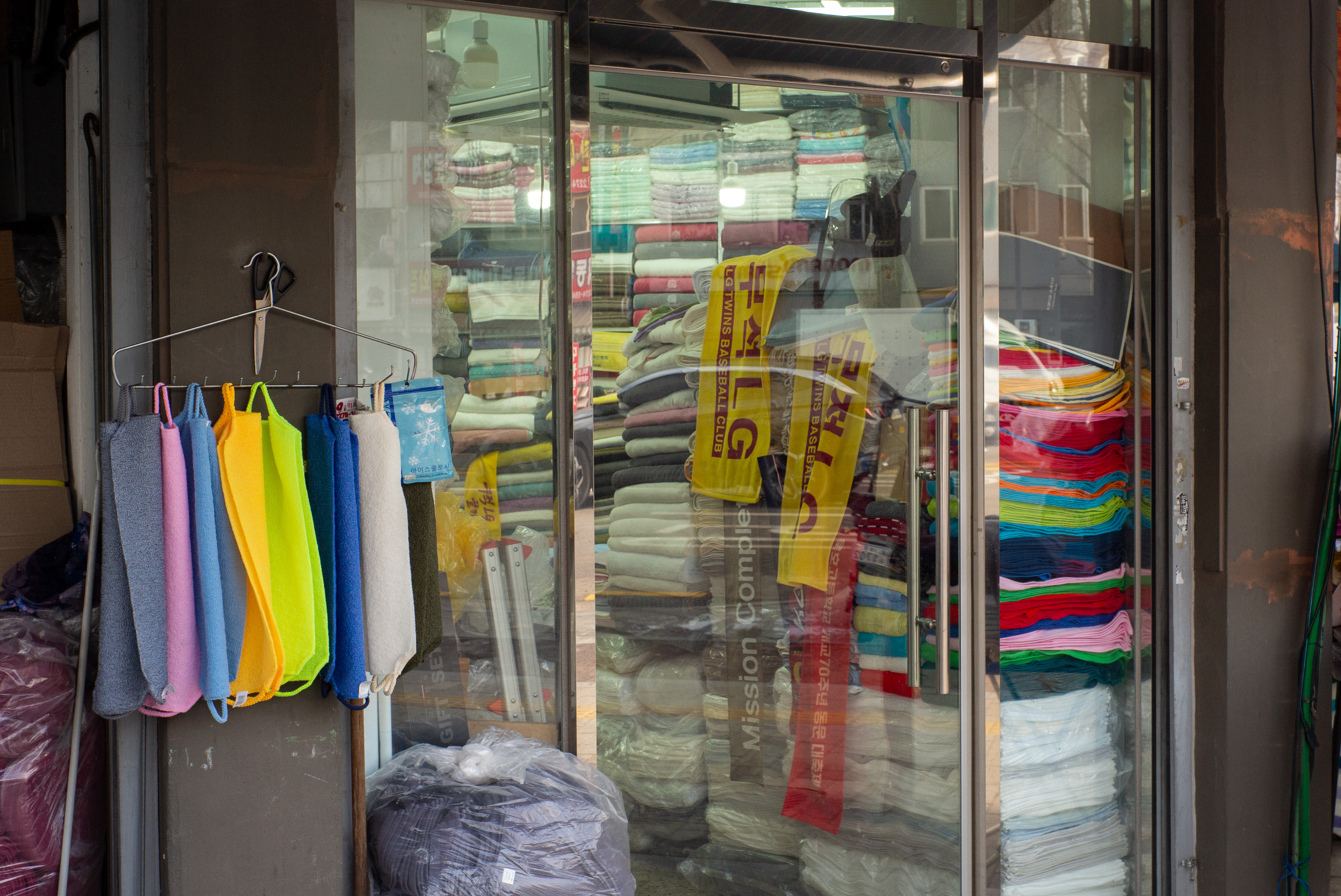 화려한 색상의 이태리 타월들이 걸려 있는 시장 상점의 유리문 안쪽으로 가득 쌓인 수건들
