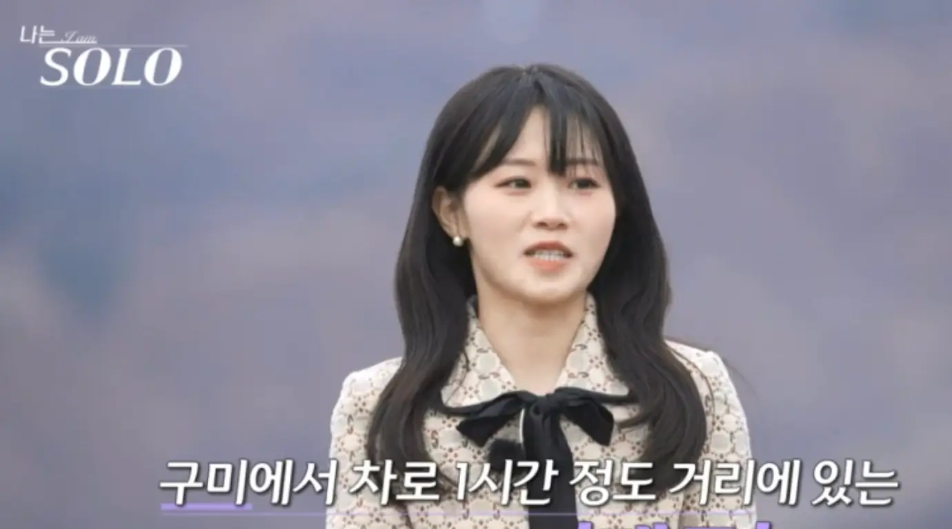 나는 솔로-자연배경 검은리본이 달린 베이지색 원피스 긴웨이브머리를 하고 말하는 현숙