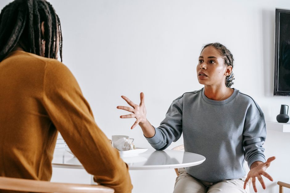 Young black woman sitting at table with man and talking to each other in modern room