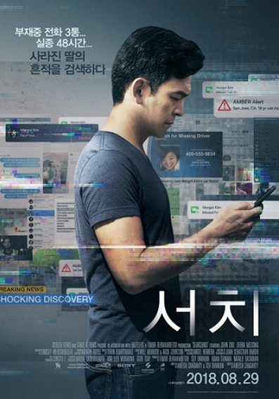 한 남자가 옆으로 서서 핸드폰 화면을 보고 있다.