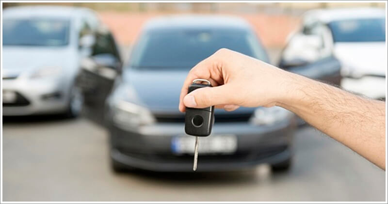 시동을 걸어놓은 자동차와 차 앞에서 손으로 차키를 들고 있는 사진