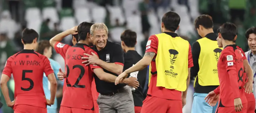 사우디전- 승리에 기뻐하며 회색바지 검은티를 입은 클린스만과 붉은 유니폼을 입은 대한민국 대표선수들이 달려가 안기는 모습