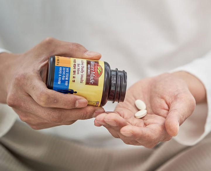 남성이-네이처메이드-종합비타민-두알을-손에-덜고-있습니다.