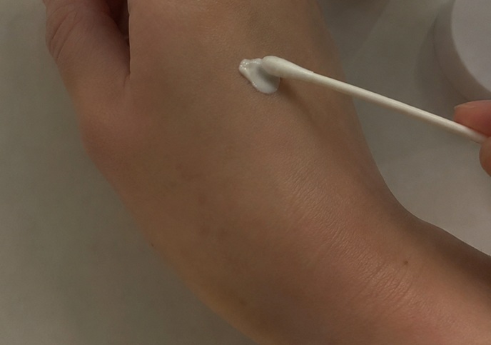 면봉으로 멜라토닝 크림을 손등에 소량 찍어 바르는 모습의 사용 후기 사진