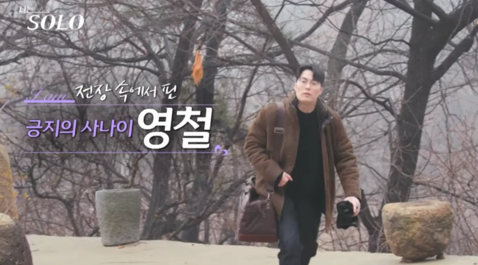 나는 솔로-나무들으리 뒤로하고 갈색 코트에 갈색 가방을 오른팔에 메고 검은티에 검은 바지를 입고 걸어올라오는 영철