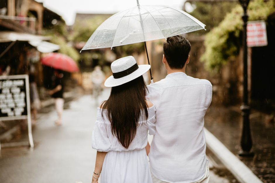 A couple seen from behind walking under an umbrella on a rainy day in the city.