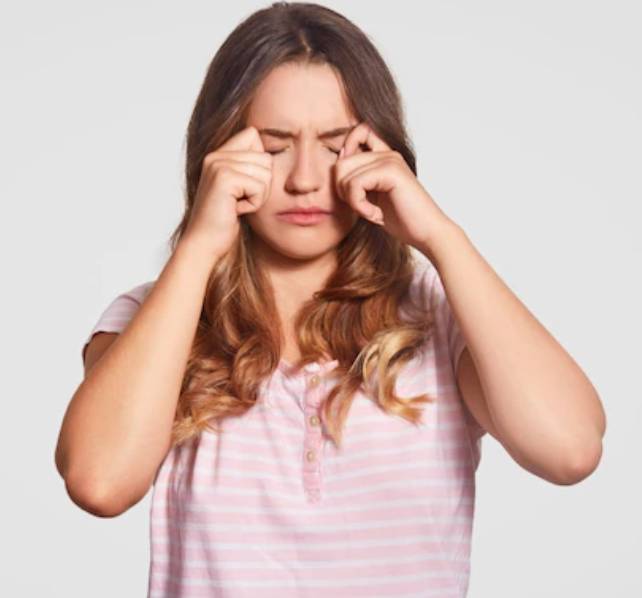 눈을 비비고 있는 분홍색 줄무늬 옷을 입은 금발머리 여성