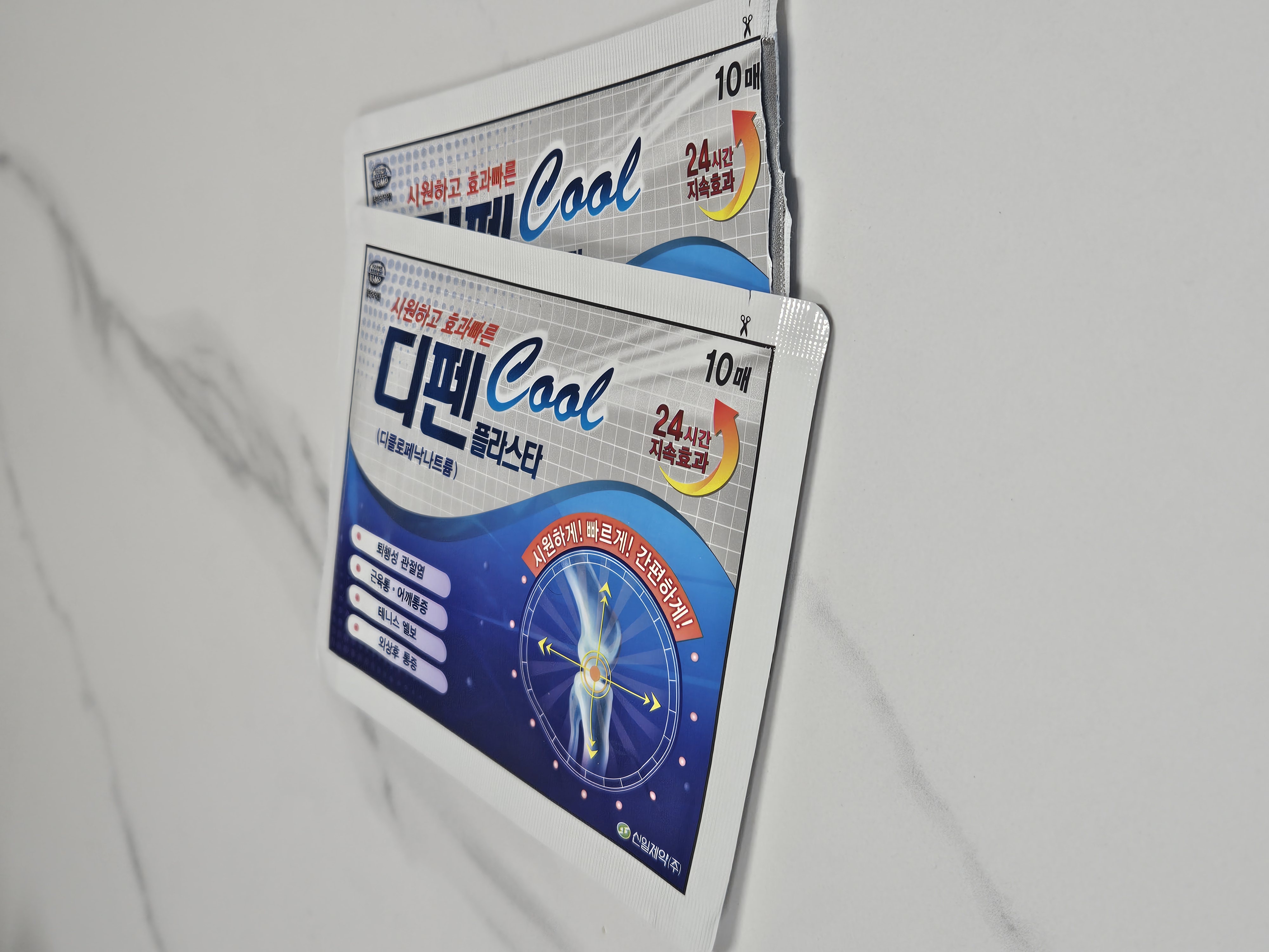 대리석 바닥 위에 놓인 근육통 완화용 디펜 쿨 파스 2팩