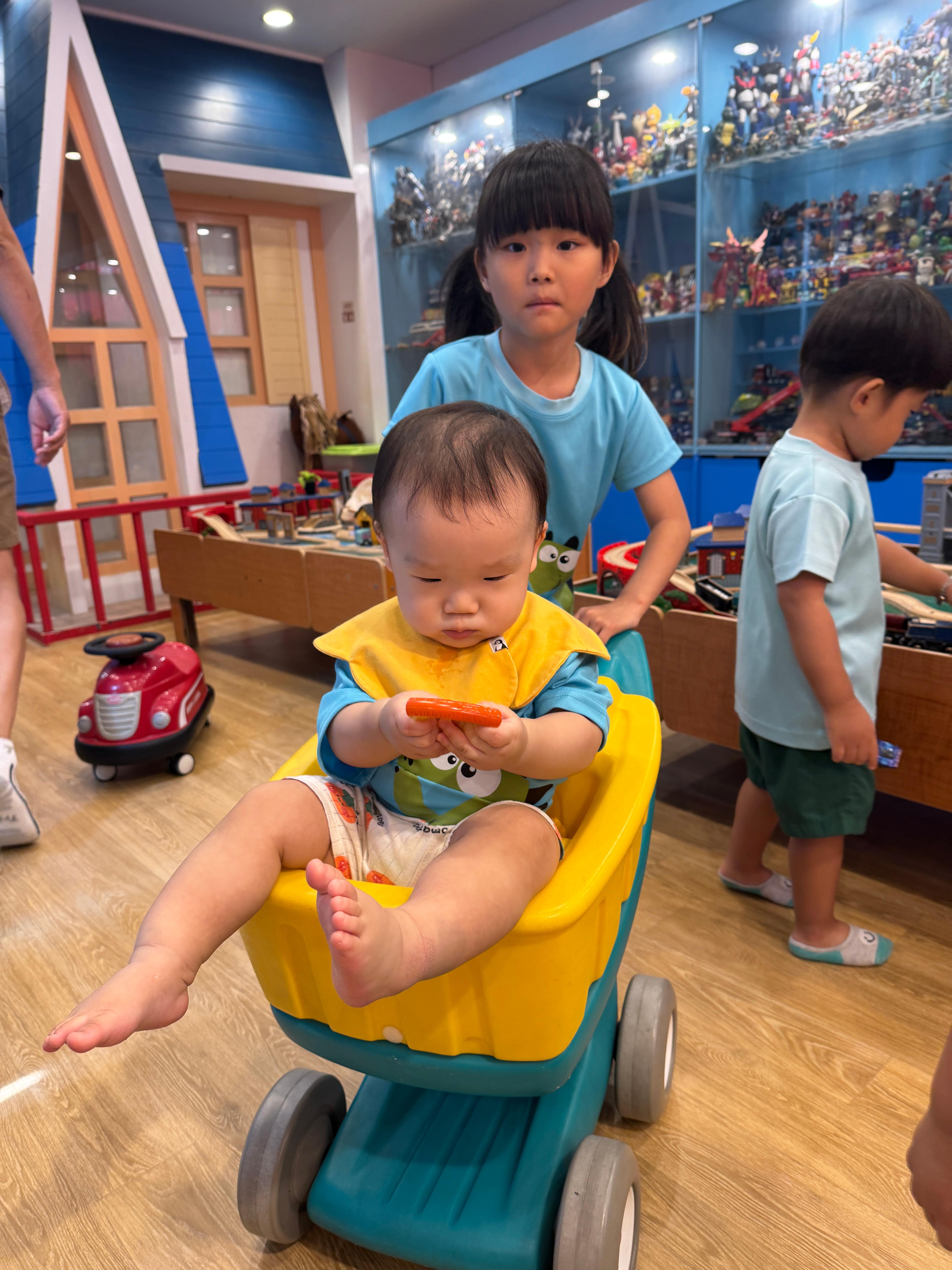 어린이집 누나가 밀어주는 쇼핑카드를 타고 있는 11개월 아기