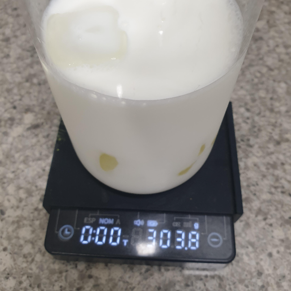 얼음과 우유 300g이 든 컵이 저울 위에 올려져 있다.