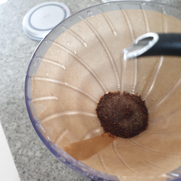 드리퍼 안의 분쇄된 원두를 뜸 들이기. 드리퍼로 물을 붓고 있다.