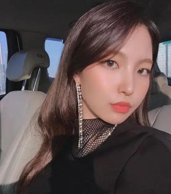 싱어게인3- 검은옷을 입고 의자에 앉아 갈색 생머리를 늘어뜨리고 오른쪽 귀에 어깨까지 오는 긴 큐빅 귀걸이를 한채 오른쪽으로 얼굴을 돌린상태에서 눈은 정면을 응시하는 27호