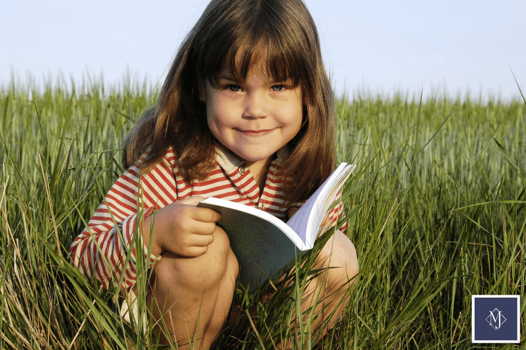 자연 속에서 편안하게 앉아 책을 읽으며 생각에 잠긴 초등 저학년 아이의 모습