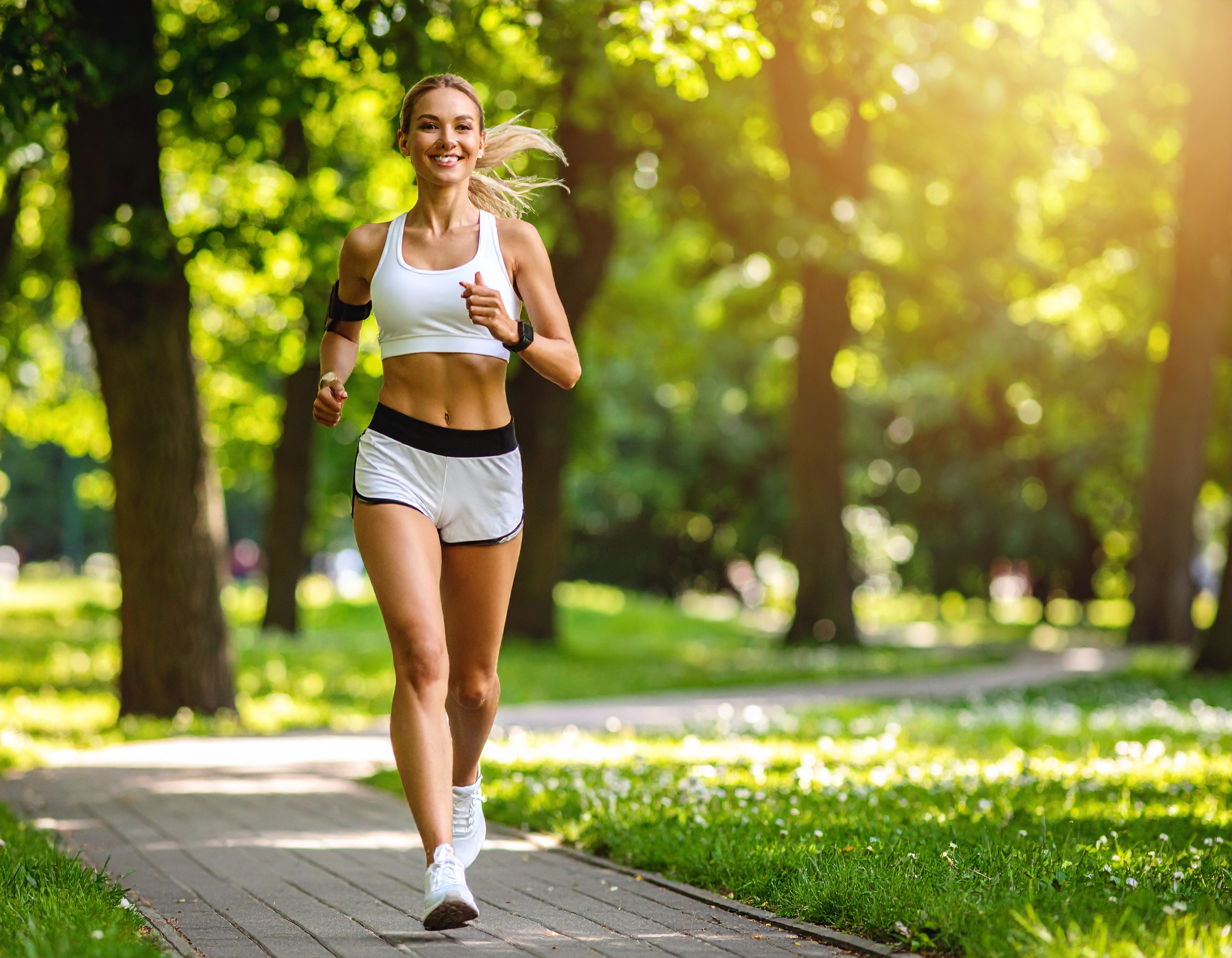 공원에서 밝은 표정으로 조깅 중인 여성, 녹음이 우거진 자연 배경