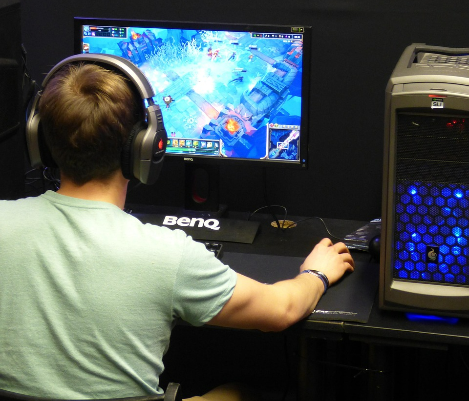 게임 기획자가 실제로 게임을 해보는 모습입니다. 컴퓨터 모니터 화면에는 게임이 실행되고 있으며 게임 기획자는 헤드셋을 끼고 게임을 하고 있습니다.