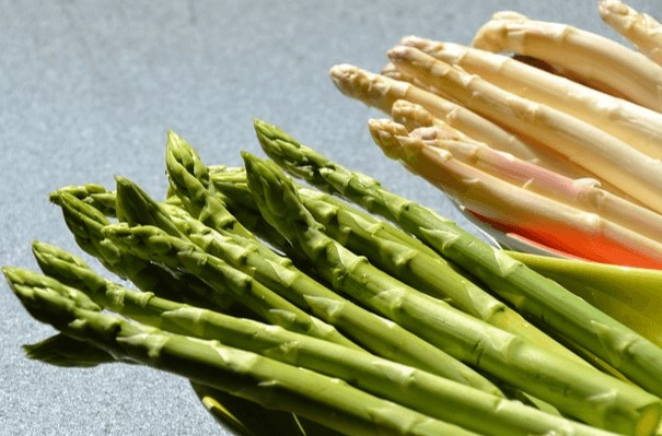 초록색 아스파라거스들과 하얀색 아스파라거스들이 15개씩 각각 그릇에 담겨있다.