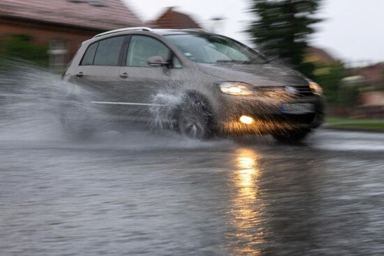 갈색-승용차가-빗길에-물을-튀기며-지나가는-모습
