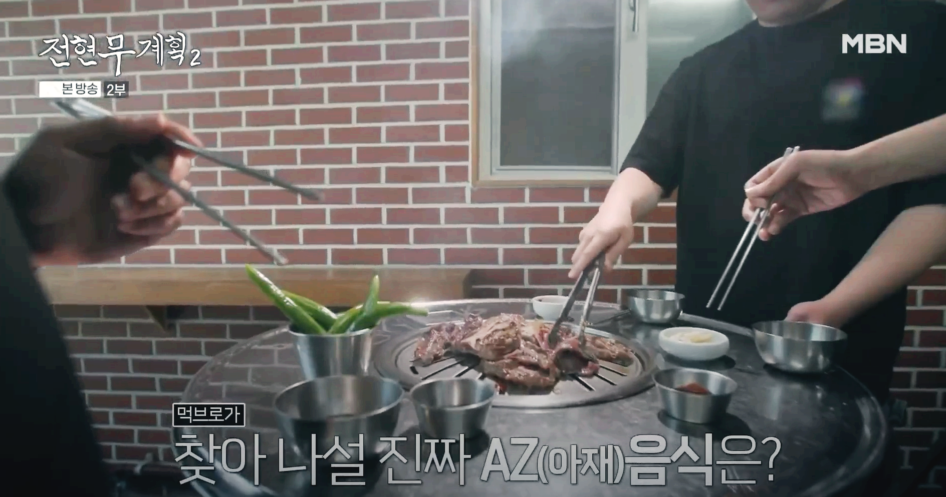 심플한 상차림의 드럼통 불판 위에 사람들이 서서 소갈비를 굽고 있는 전현무계획2 방송장면