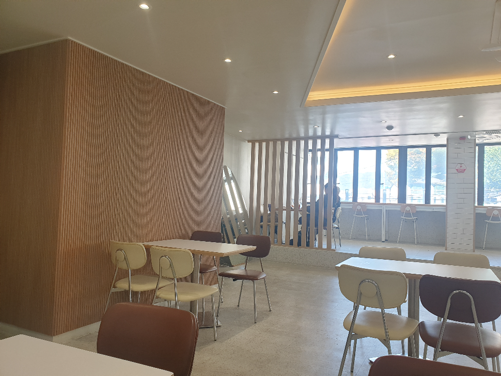 2층 우드 파티션과 흰색 테이블, 넓은 창에는 바형 테이블이 있다.