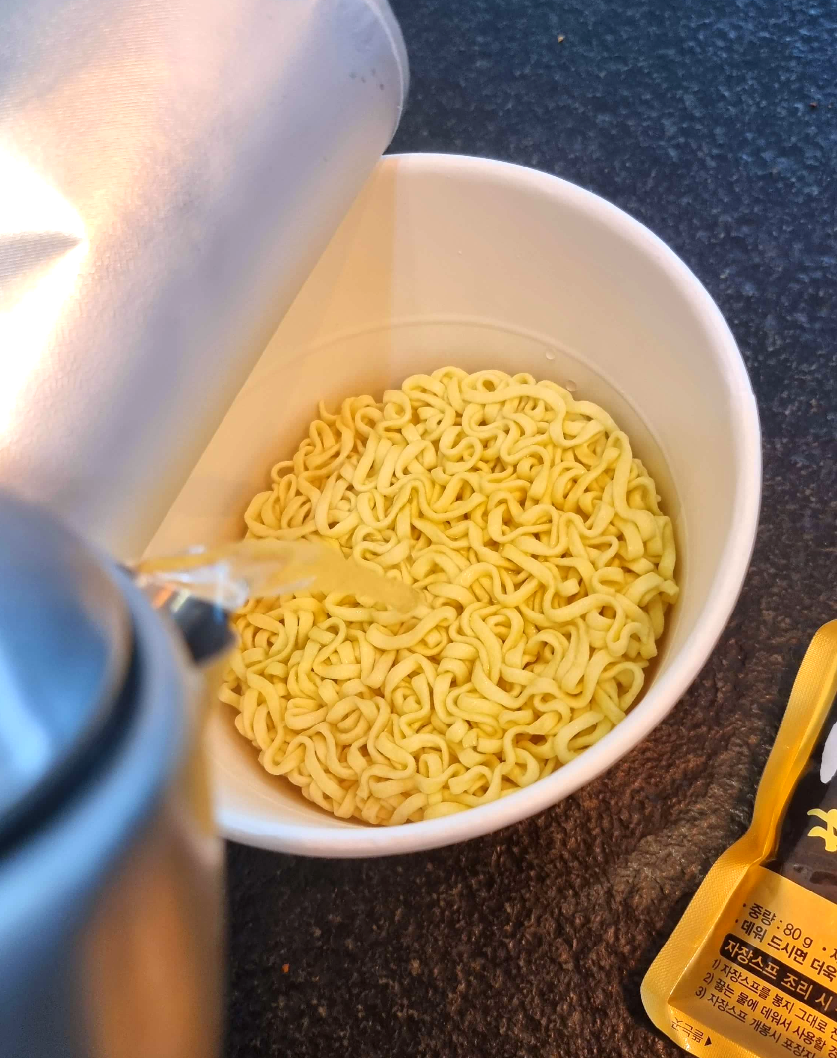 짜장 컵라면에 물을 붓고 있다