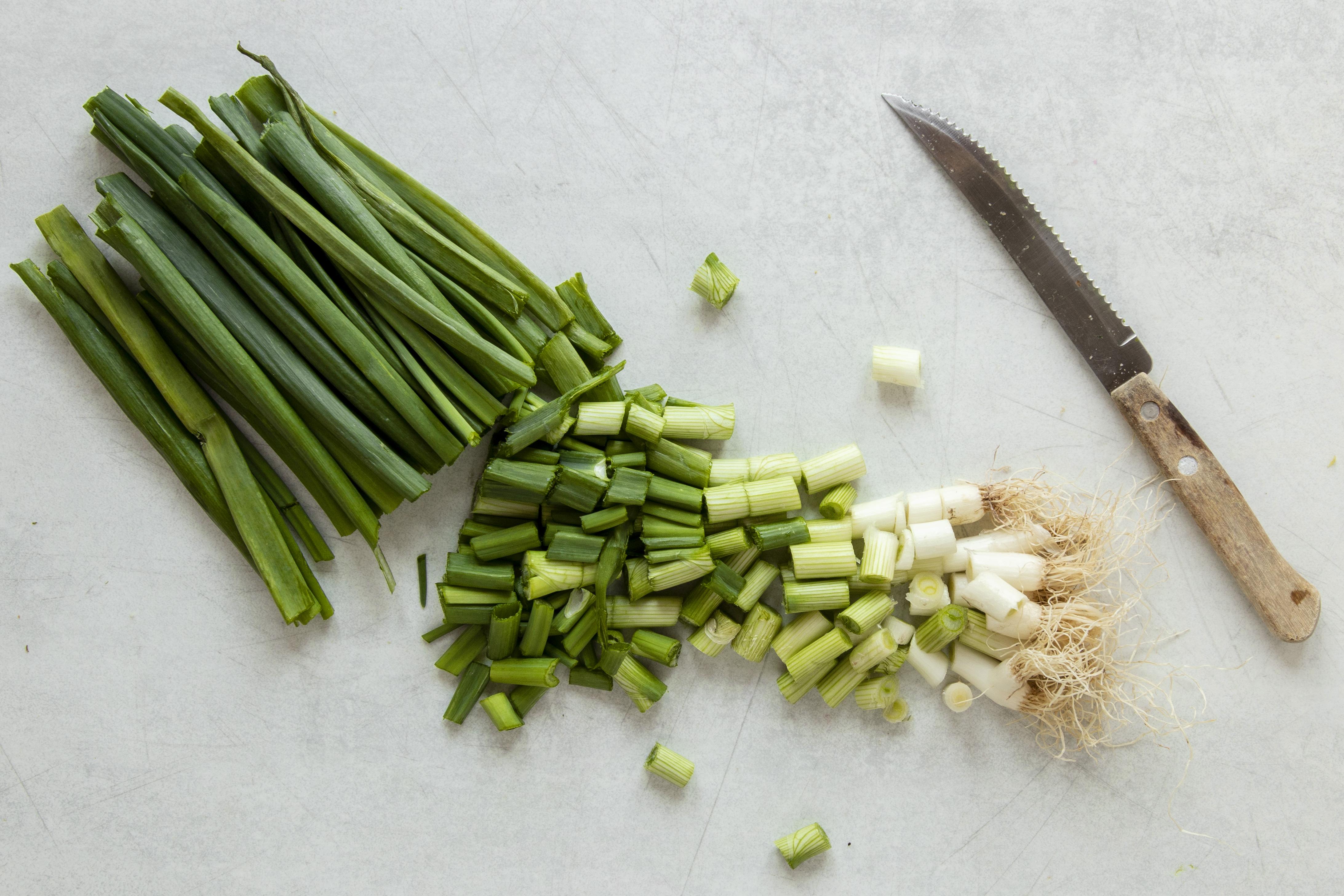 바닥에 파를 놓고&#44; 뿌리의 흰부분과 뿌리의 초록부분&#44; 그리고 파의 윗부분을 칼로 잘라 놓은 사진 - 소음인(少陰人)에게 맞는 음식