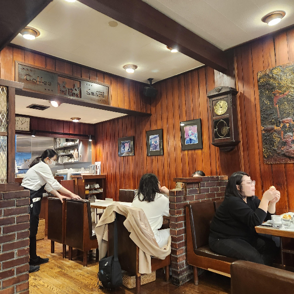 목재로 된 내부. 예전 우리나라 경양식 집 같다. 직원이 정리를 하고 있고 손님들은 담소를 나누고 있다.